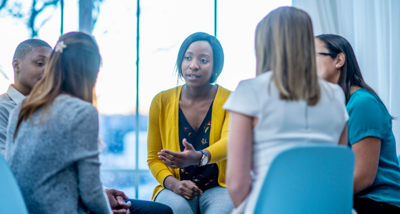 Group of people sitting in a circle chatting at a support group